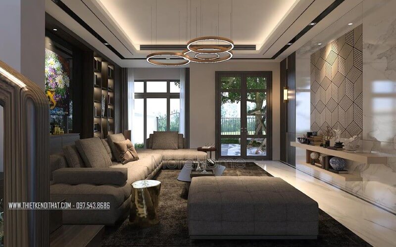 Sắp xếp nội thất phòng khách ấn tượng với cách kết hợp hài hòa giữa sắc trầm và sáng cùng hệ cửa kính lớn giúp không gian trở nên thông thoáng, sang trọng. Thiết kế nội thất